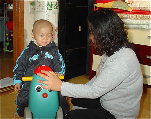 동준이와 동준이 엄마, 뒷편에 '호흡기 1급 장애'로 고생하는 사이버지가 쓰시는 '의료용 산소통'이 보인다. 